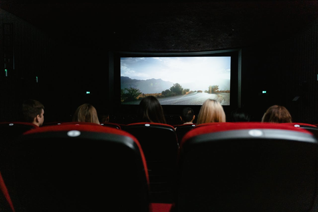 Crafting Captivating Headlines: Your awesome post title goes here View from behind of people watching a movie in a cinema with red seats and a large screen.
