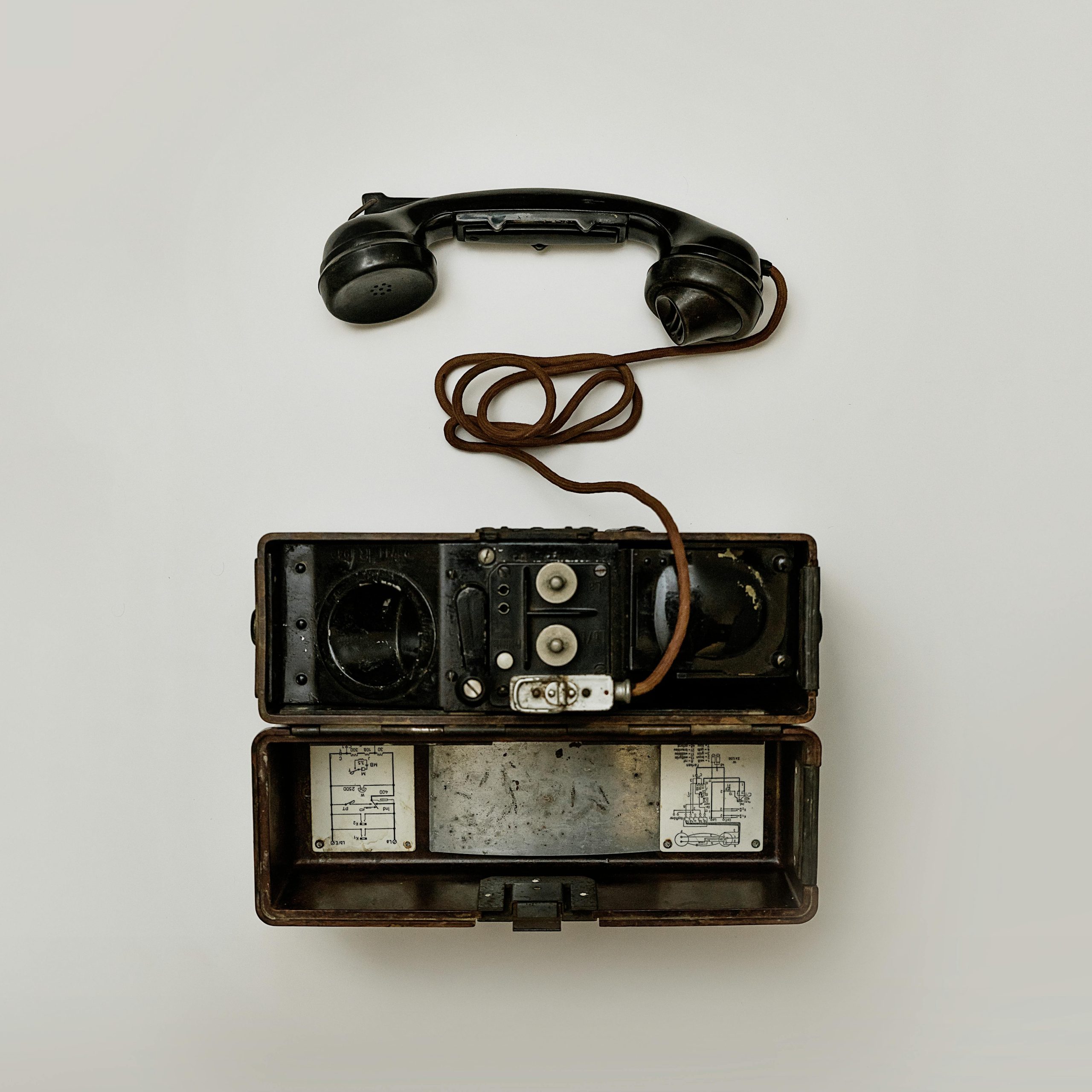 Close-up view of a vintage military field telephone with receiver and wires, showcasing antique technology.