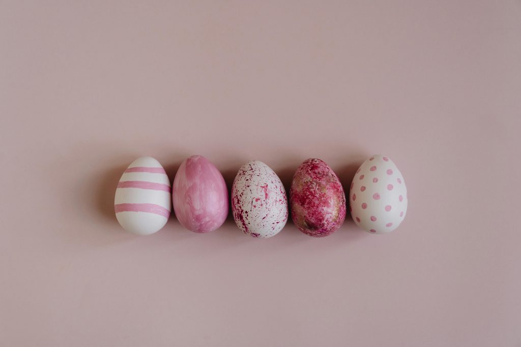 Caccia alle uova di pasqua Decorative Easter eggs displayed on a soft pink background, showcasing artistry and tradition.